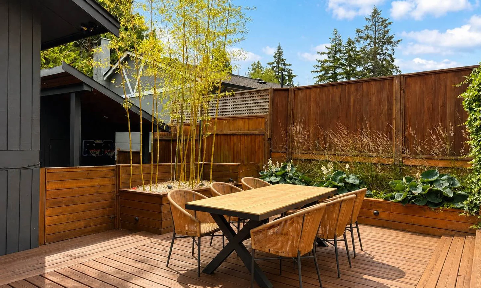 Private cedar deck with an outdoor dining table and chairs surrounded by bamboo planters