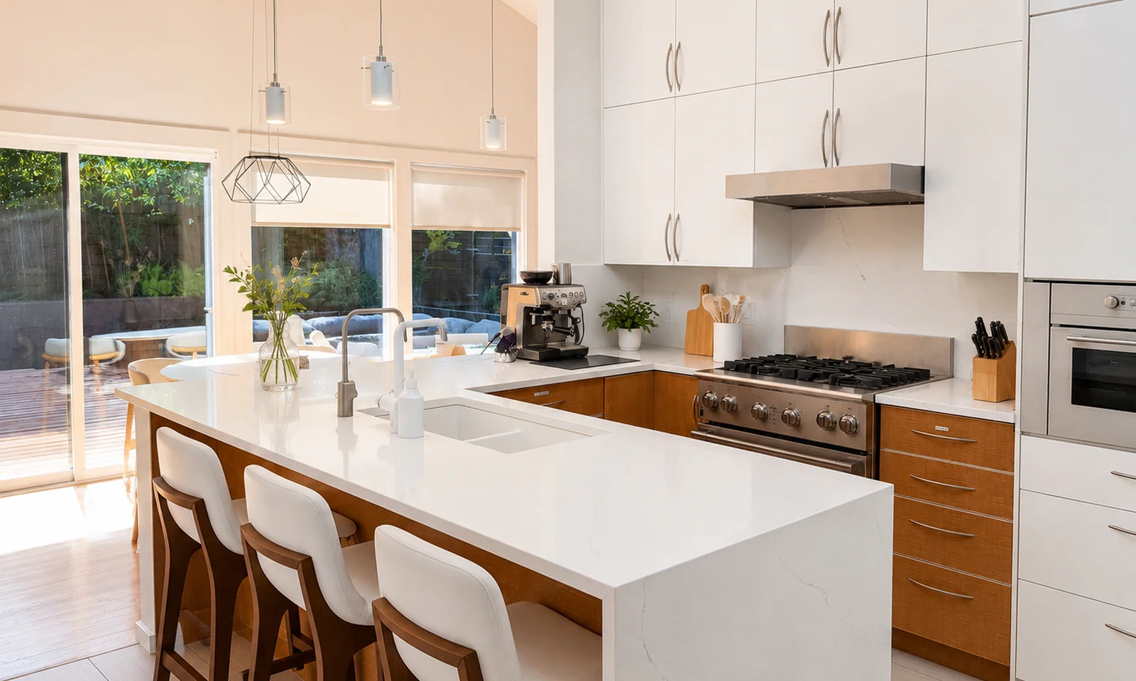 Full kitchen in the suite with a stone-topped island, three counter stools, gas range, wall oven, and espresso machine