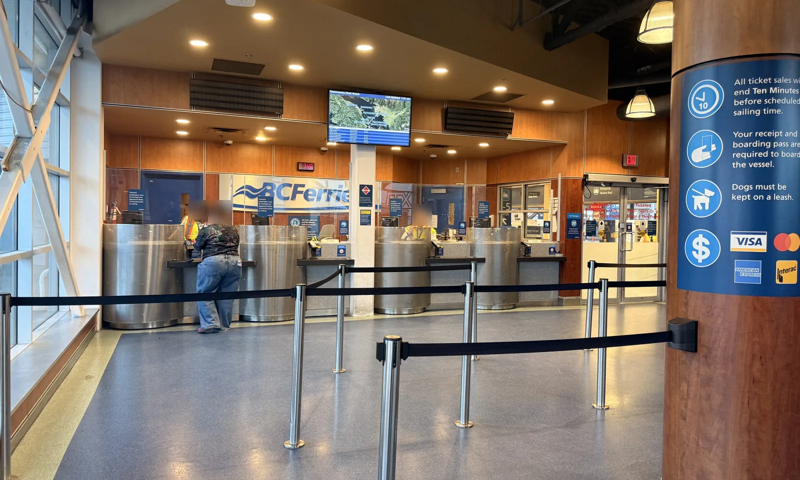 Staffed walk-on ticket counters inside the Tsawwassen Ferry Terminal, with queue barriers and a sign stating that ticket sales end ten minutes before sailing